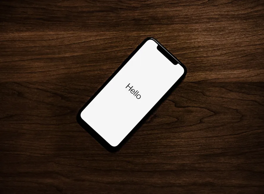 Smartphone posé sur un bureau en bois affichant « Hello »